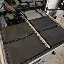 Load image into Gallery viewer, Black zippered bags inside a vehicle storage compartment.