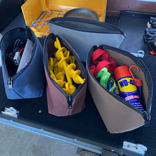 Load image into Gallery viewer, Four open pouches containing various items on a black surface