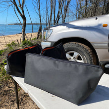 Load image into Gallery viewer, Black canvas rope bag on a table with a beach and vehicle in the background