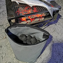 Load image into Gallery viewer, Portable grill with charcoal bag and glowing coals with a fish cooking
