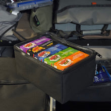 Load image into Gallery viewer, Black pouch with shapes boxes inside, attached to a vehicle&#39;s storage compartment.