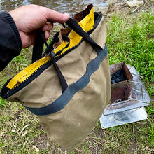 Load image into Gallery viewer, A well used canvas charcoal bag by the river