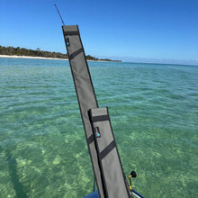 Load image into Gallery viewer, Grey fishing rod covers on a boat, with clear turquoise water and a tropical shoreline in the background.