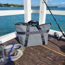 Load image into Gallery viewer, Fishing tackle bag with black handles on a wooden jetty by the water.