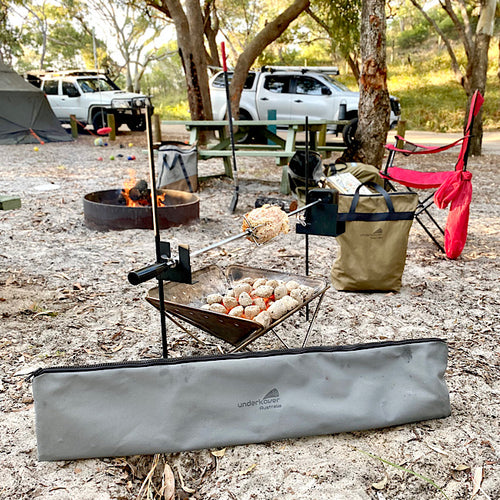 rotisserie cooker with meat over campfire