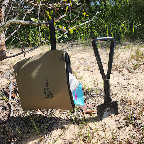 canvas bag hanging from tree next to shovel 