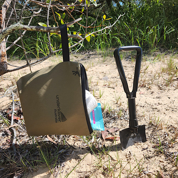 canvas bag hanging from tree next to shovel 