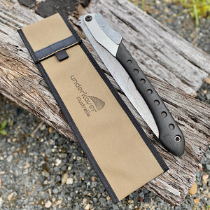 canvas bag and saw sitting on log