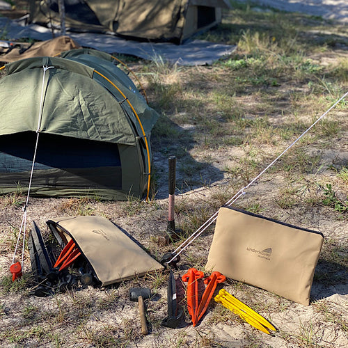 Canvas bag on sand next to swag