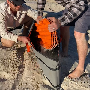 men putting recovery tracks into canvas storage bag